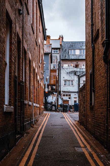 A straight residential street in Finchley lined with parked cars on both sides, including sedans, vans, and small trucks. The pavement is clear, with a variety of houses featuring brick façades and t